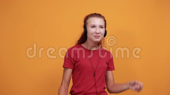穿红色衬衫的漂亮女士听音乐手拿耳机微笑着视频的预览图