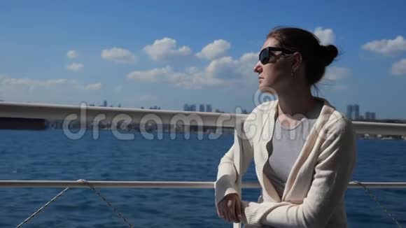 女孩坐在甲板扶手上享受海上航行视频的预览图
