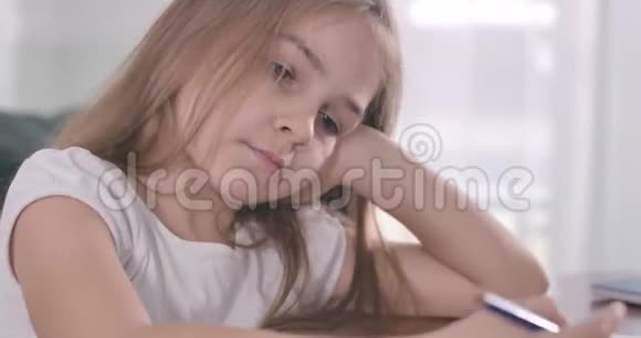 美丽悲伤的白种人女孩用手抱着头的特写脸困乏的学童坐在桌子旁视频的预览图
