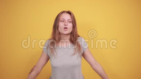 穿灰色t恤的布鲁内特女孩在橙色背景下表现出情绪视频的预览图