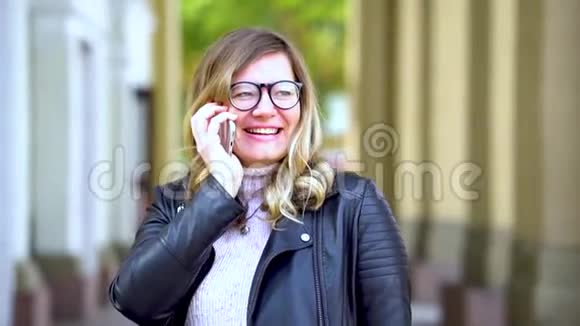一个戴眼镜的漂亮女孩在智能手机上说话视频的预览图