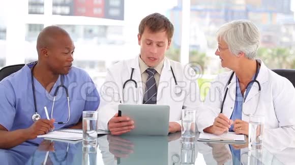 一位严肃的医生和同事谈论平板电脑视频的预览图