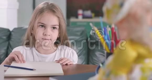 漂亮的白人女孩向镜头解释了一些事情心情不好的孩子像坐在那儿一样有感情地说话视频的预览图