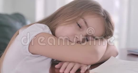 一张漂亮的白人女孩在阳光下睡在桌子上的特写脸精疲力竭的学童在运动旁边休息视频的预览图