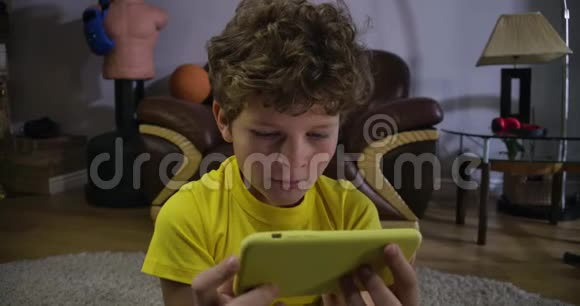 在智能手机屏幕上观看喜剧表演的白人卷发男孩的特写脸可怜的孩子笑了发电视频的预览图