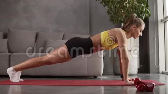 年轻健康运动的金发女孩黄色上衣的猪尾黑色短裤做交叉腿在木板位置锻炼视频的预览图