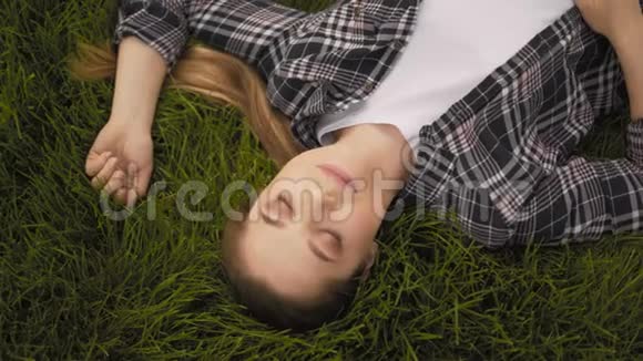 年轻开朗的女孩躺在草地上笑视频的预览图