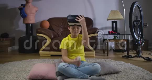 男性白种人青少年携带VR耳机并使用遥控器打开游戏的肖像儿童试图视频的预览图