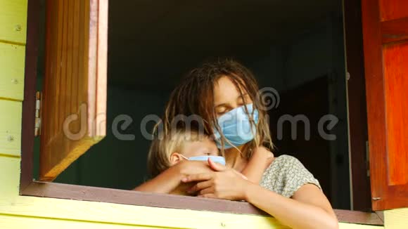 妈妈和女儿戴着防护面具在窗户里传染病检疫病毒COVID19视频的预览图