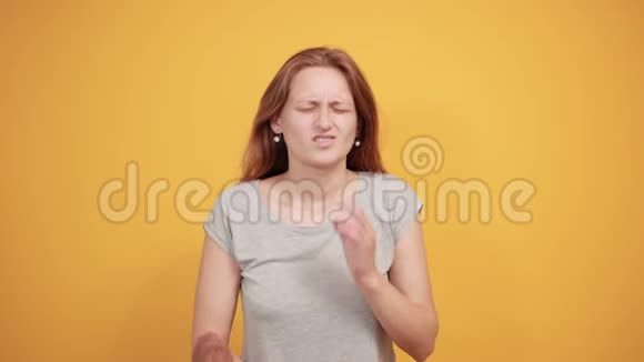 穿灰色t恤的布鲁内特女孩在橙色背景下表现出情绪视频的预览图
