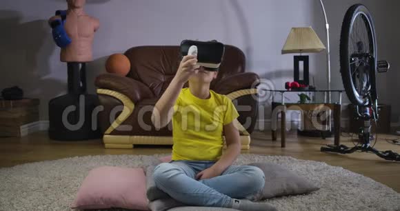 年轻的白种人青少年卷发在VR耳机持有遥控器和环顾四周儿童使用虚拟视频的预览图