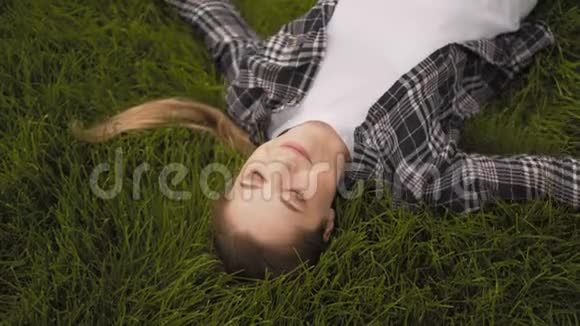 年轻快乐的女孩躺在草地上微笑着视频的预览图