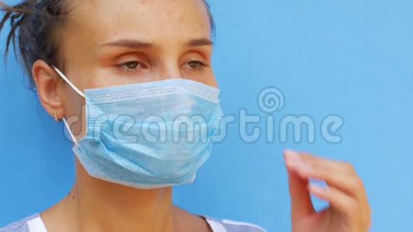 一个戴着面具的年轻女人用纸巾吹鼻子视频的预览图