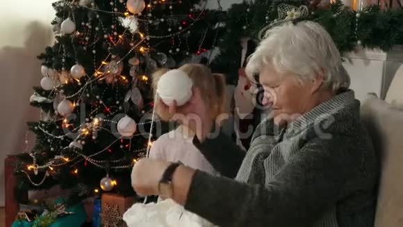 女人和圣诞树旁边的小女孩玩视频的预览图