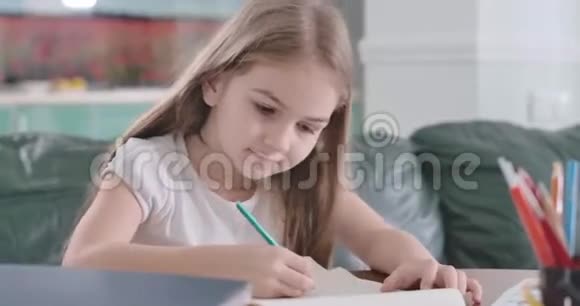 微笑的白种人孩子在家里的桌子上做作业的肖像体贴的女学生解决数学问题视频的预览图