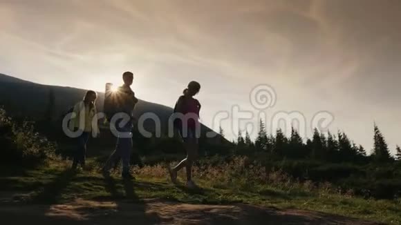 走向冒险带着背包的朋友在日落时沿着山路散步视频的预览图