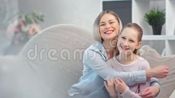 可爱的微笑的年轻妈妈拥抱着可爱的女儿在灯光的包围下摆着姿势视频的预览图