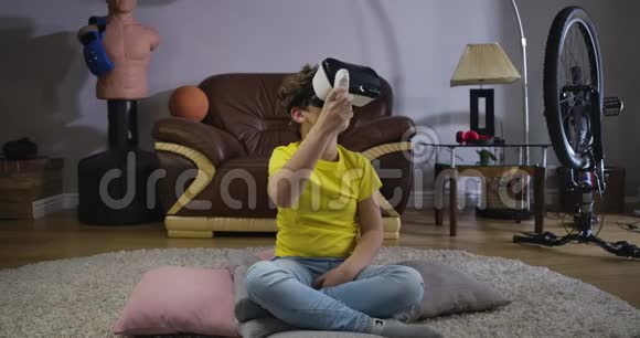 男性白种人青少年戴VR耳机使用遥控器玩游戏孩子们环顾四周微笑着视频的预览图