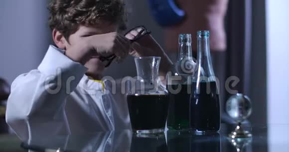白种人男孩戴着眼镜用液体看着烧瓶从事化学实验的年轻天才视频的预览图