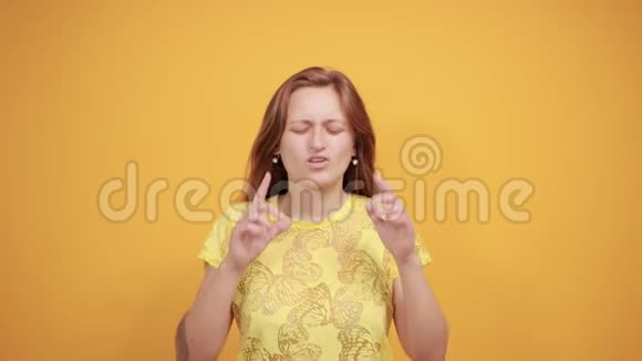 在橙色背景下穿黄色t恤的布鲁内特女孩表现出情感视频的预览图