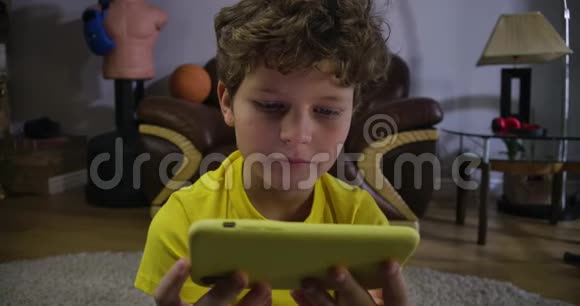 专心的白人男孩在智能手机屏幕上看一些有趣的东西快乐的孩子看着屏幕笑视频的预览图