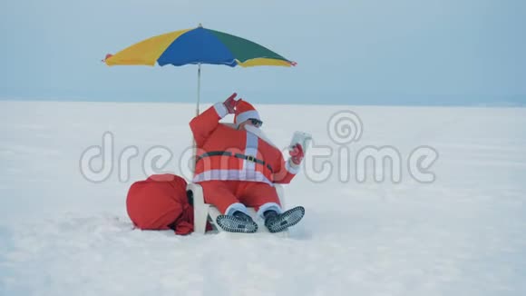圣诞老人坐在雪地里的躺椅上的录像视频的预览图