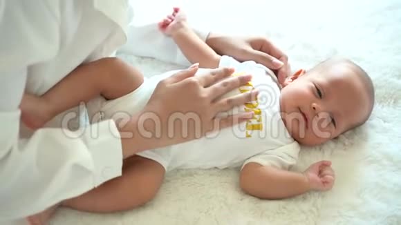 可爱的亚洲新生儿男孩躺在床上母亲手在室内的腹部视频的预览图