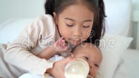 亚洲一家可爱的女孩妹妹从奶瓶中喂奶给刚出生的弟弟然后躺在床上视频的预览图