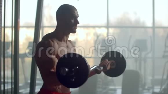 一个赤裸的躯干和有力的身体和放松的肌肉的人举起一个杠铃重量在视频的预览图