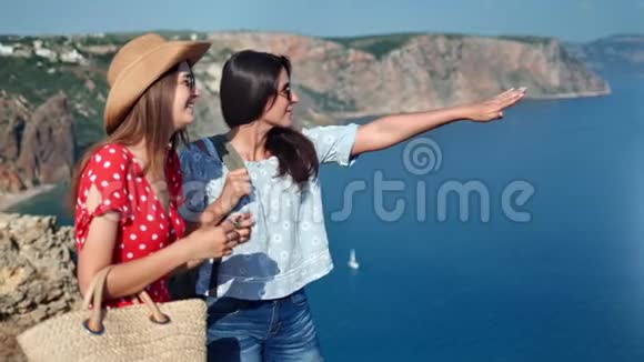 两个迷人的休闲旅游女孩欣赏美丽的海景从山顶中射视频的预览图