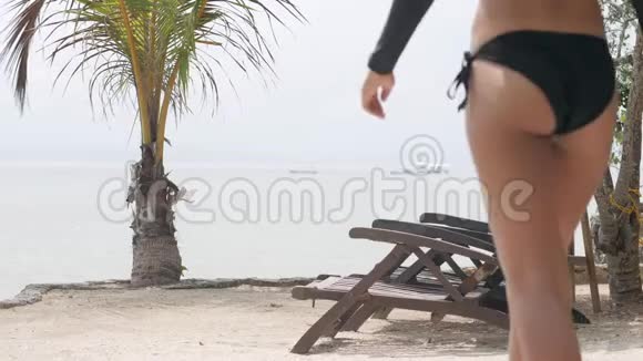 苗条的女人穿着性感的泳装在海滩度假村散步坐在椅子上视频的预览图
