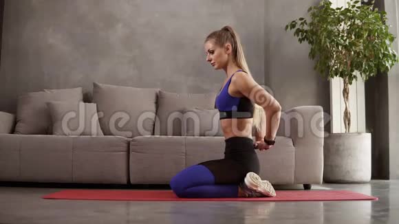 年轻女性在家训练瑜伽坐在沙发前的垫子上伸展背部肌肉坐着时弯曲视频的预览图