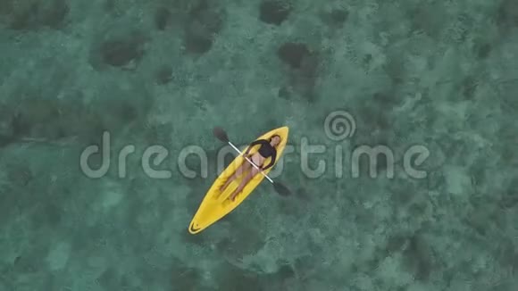 空中镜头一位女性皮划艇在夏天躺在海里的黄色皮划艇上视频的预览图