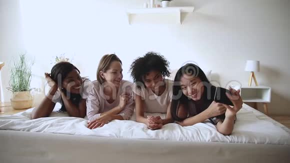快乐的多民族千禧女性一起躺在床上自拍视频的预览图