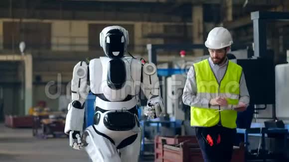 工厂工人用平板电脑检查行走的机器人视频的预览图
