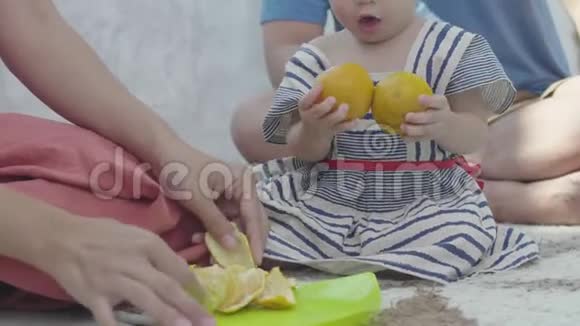 一位亚洲母亲正在喂橘子让她的女儿快乐地吃视频的预览图