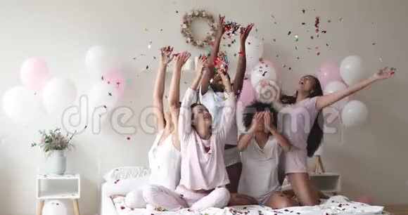 无忧无虑的年轻女性庆祝睡衣派对扔纸屑视频的预览图