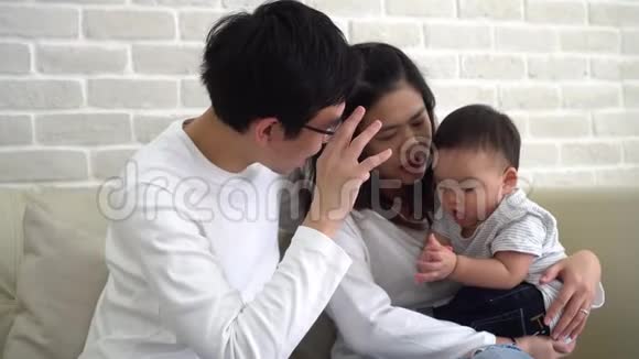 亚洲家庭的父母和儿子在家里的沙发上玩耍视频的预览图