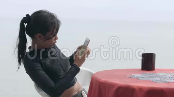 亚洲女人在热带海滩附近的桌子上拍照一个杯子视频的预览图