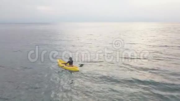 女人坐在皮艇上坐在卢托斯的位置上在平静的海洋中冥想无人机视图视频的预览图