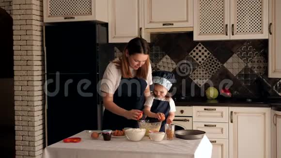 一个母亲和一个女儿一起准备面团他们把鸡蛋打碎成一个碗视频的预览图