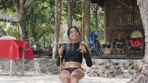 年轻快乐的女人穿着性感的泳装喜欢骑在秋千上视频的预览图