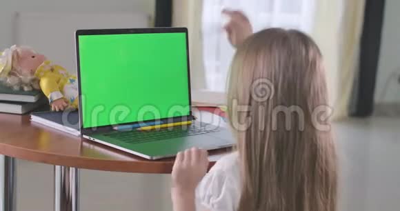 白人女孩用绿色屏幕看笔记本电脑的背面视图在网上学习或使用社交媒体或视频的预览图