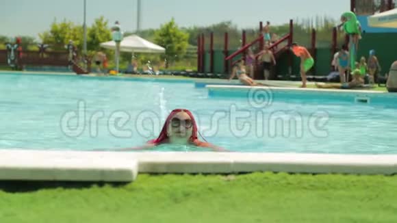 一位穿着白色泳衣的年轻女子正从游泳池的边缘航行视频的预览图