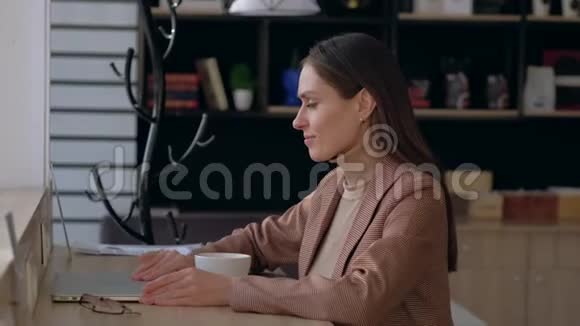 戴眼镜的漂亮女人打开笔记本电脑在咖啡店喝咖啡视频的预览图
