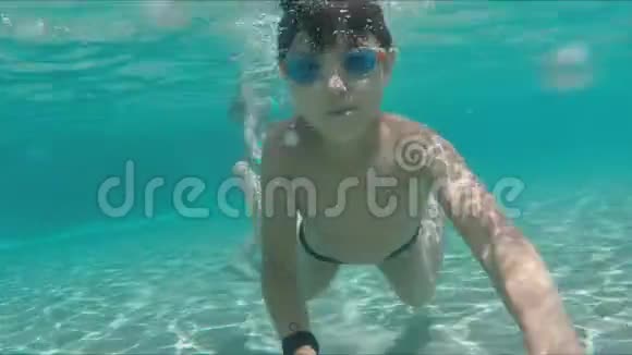 快乐的男孩在游泳池里向前游微笑着视频的预览图