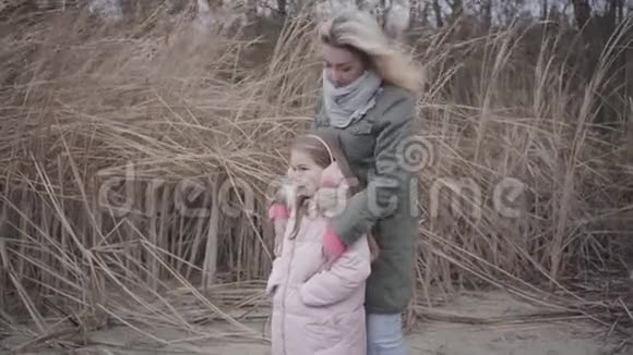 美丽的白种人女人和她的女儿穿着粉红色的衣服站在风中望着远方视频的预览图
