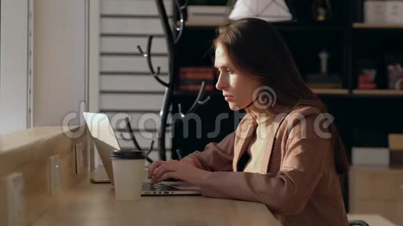 坐在酒吧旁边的漂亮女人使用笔记本电脑在键盘上打字视频的预览图