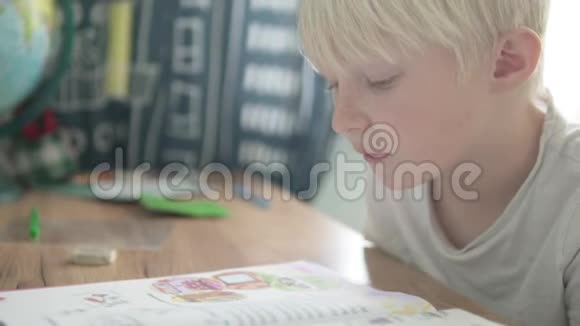 金发男孩在学校书桌上做作业视频的预览图