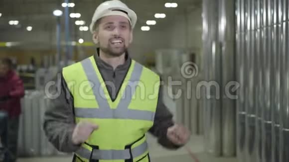戴着防护头盔的白人男性工人在钢金属管道背景下跳舞的肖像快乐视频的预览图